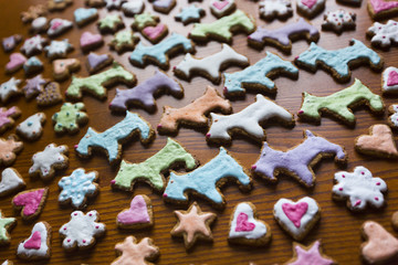Имбирное печенье в разноцветной сахарной глазури в форме собак, сердец, цветов и звезд на деревянном столе