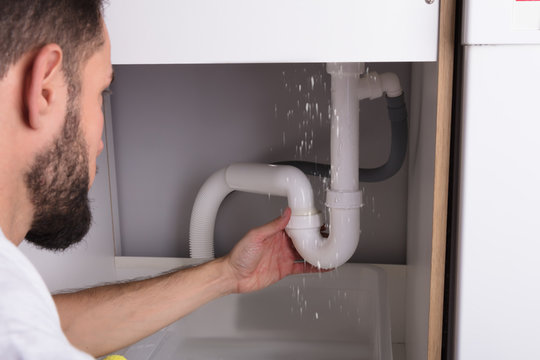 Man Looking At Sink Pipe Leakage