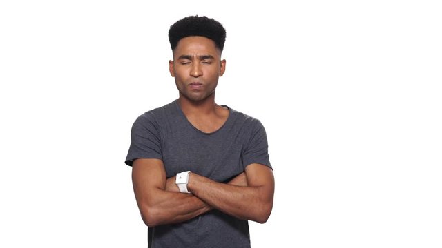 Offended displeased african man in t-shirt holding crossed arms and looking at the camera over white background
