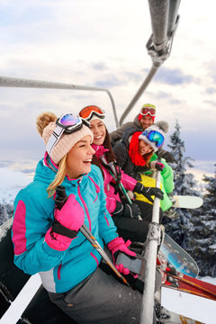 cheerful friends skiers on ski lift ride up on ski slope at snowy day