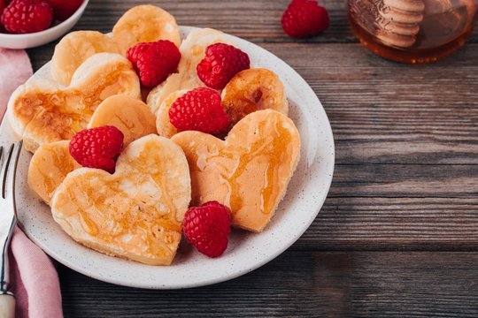 Heart shaped pancakes with raspberries and honey for St. Valentine's Day