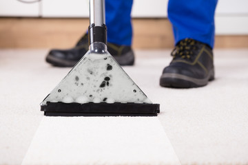Person Using Vacuum Cleaner For Cleaning Carpet