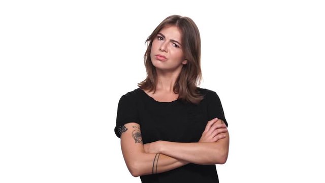 Displeased brunette woman in t-shirt holding crossed arms and disagrees with something over white background