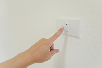 finger is turning on or off on light switch on walla. Copy space.