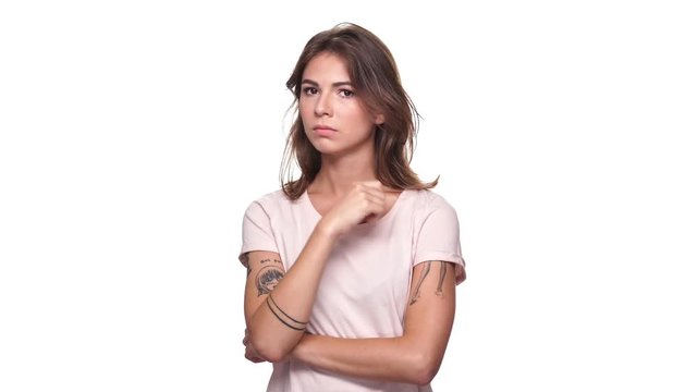 Young brunette woman in t-shirt picking one's nose over white background