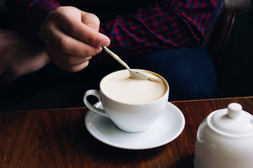 coffee in hands. woman relaxing near the window in a vintage restaurant. caffeine is invigorating. cappuccino in a glass.