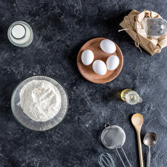 top view of arranged kitchenware and ingredients for bread baking on dark marble surface