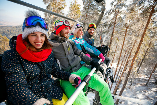 Smiling friends skiers and snowboarders on ski lift