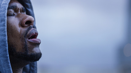 Hooded male athlete sweating as he gets his breath back after a workout