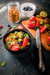 Healthy breakfast with muesli or granola with nuts and fresh berries and fruits - strawberry, blueberry, kiwi, on dark blue table, copy space