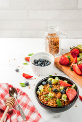 Healthy breakfast with muesli or granola with nuts and fresh berries and fruits - strawberry, blueberry, kiwi, on white table, copy space