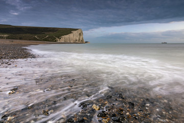 Sea and pebbles in Cuckmere Haven with the Seven Sisters cliffs