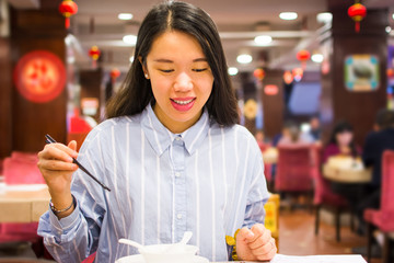 Asian woman enjoying Chinese food in Chinese restaurant