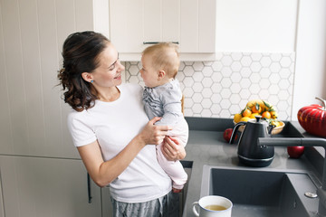 Young mother holding baby in kitchen. Hapy maternity concept