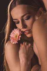 tender couple hugging and holding gerbera flower, isolated on brown