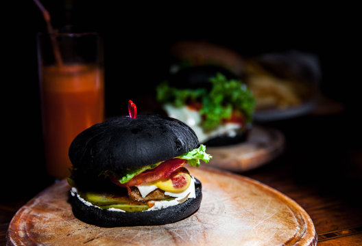 Modern black burger on wooden board. Toned picture