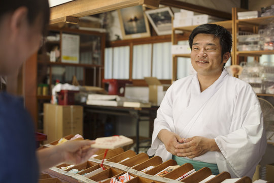 Salesman wearing white kimono at Shinto Sakurai Shrine, Fukuoka, Japan.
