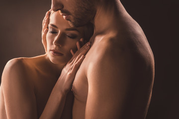 naked tender couple embracing with closed eyes, on brown