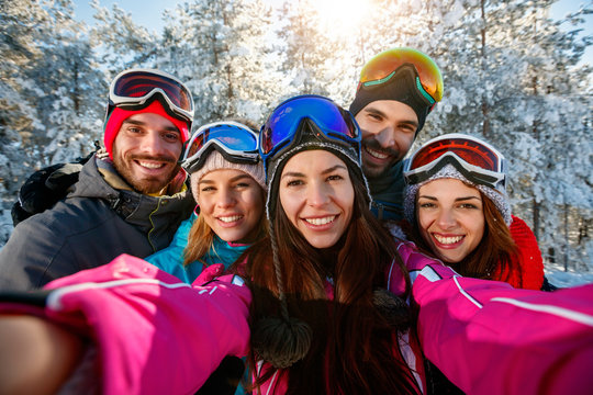 friends skiers on winter holidays taking photo with mobile phone