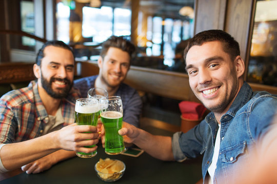 friends with green beer taking selfie at pub