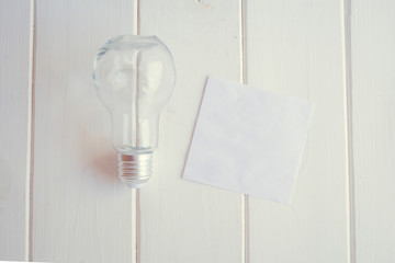 A light bulb rests on a white wooden table. The concept of new ideas