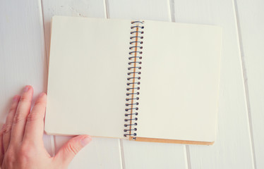 An empty notebook lies on a writing desk. A woman's hand flips through the pages to write plans and ideas
