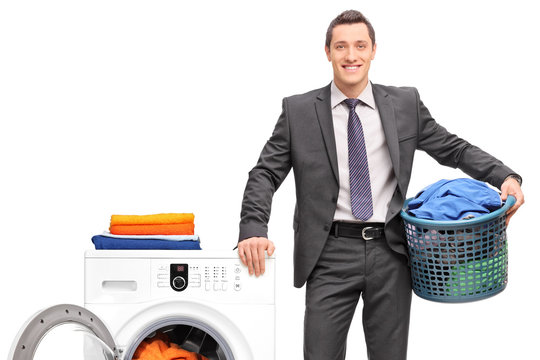 Businessman with a laundry basket next to a washing machine