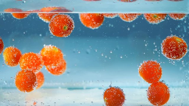 Abstract background. Red tomatoes in a blue water goes up and dowm.