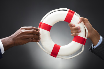 Businesspeople Holding A Lifebuoy In Hands