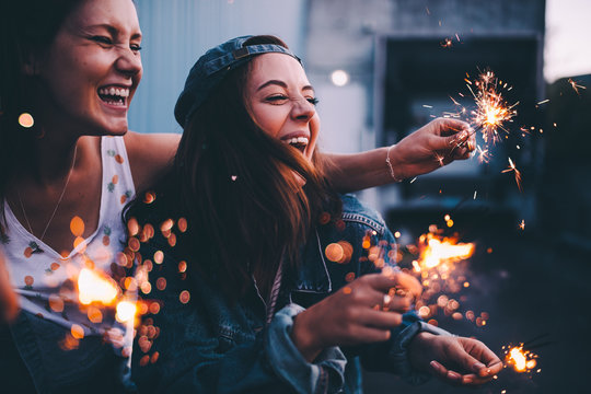 Young adult girlfriends celebrating with sparklers at night