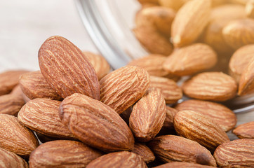 Pile of almonds spill from bottle.