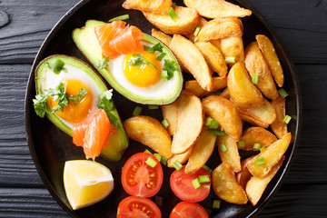 Avocado stuffed with eggs and salmon, fresh tomatoes and fried potato wedges close-up. horizontal top view