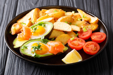 Tasty food crockpot baked avocado stuffed with eggs and salmon, tomatoes, lemon and fried potatoes close-up. Horizontal