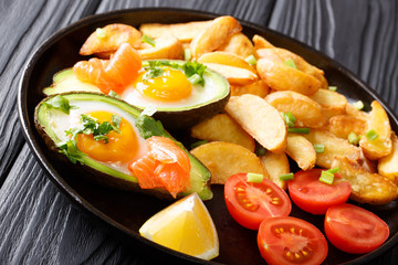 Ripe baked avocado stuffed with eggs and salmon, fresh tomatoes, lemon and fried potatoes close-up. horizontal
