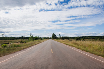 asphalt road through the rice field and clouds on blue sky in summer day