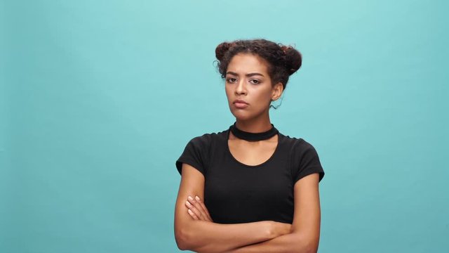 Displeased african woman in t-shirt with crossed arms disagree with something over blue background