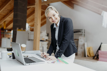 young, pretty, blonde architect is planning on the notebook and tablet the expansion of a loft
