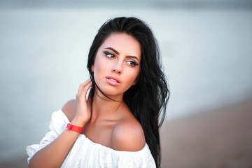 Beautiful young girl in white dress near the ocean coast brown eyes black hair portrait