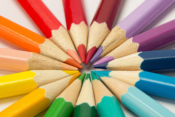 A group of pencils folded in rainbow colors in a circle on a white background