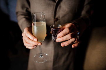 man is holding a glass and a pile with alcohol cocktails