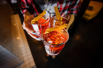 girl holds alcoholic cocktails negroni with ice and dried honeycombs