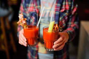 guy is holding two glasses of alcoholic cocktail Bloody Mary