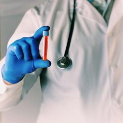 science, chemistry, biology, medicine and people concept - close up of male scientist or doctor holding test tube with blood sample making research in clinical laboratory