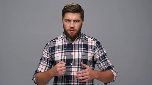 Serious bearded man in shirt ready to fight over gray background
