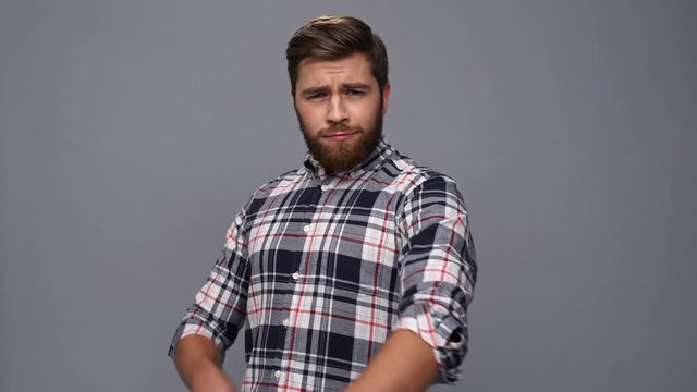 Cool bearded man in shirt holding crossed arms and looking at the camera over gray background