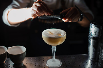 barman prepares an alcohol cocktail sour mix, adding powdered sugar