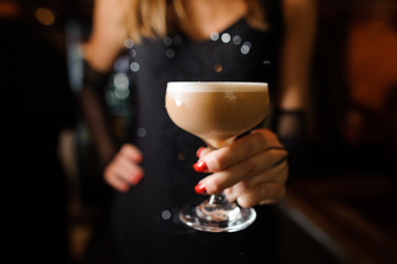 girl in a black dress holding one goblet with cocktail sour mix