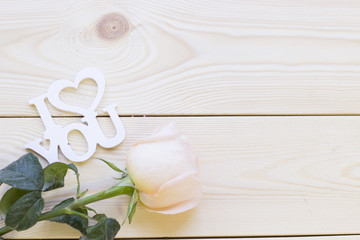 Concept of St.Valentine's Day, Love, Anniversary, Wedding. Natural wooden background with a pale cream rose and I love you inscription, top view