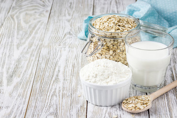 Oat flakes, oat flour and milk in glass on white background. Selective focus, space for text.