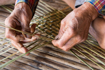 Old man hands manually weaving bamboo.